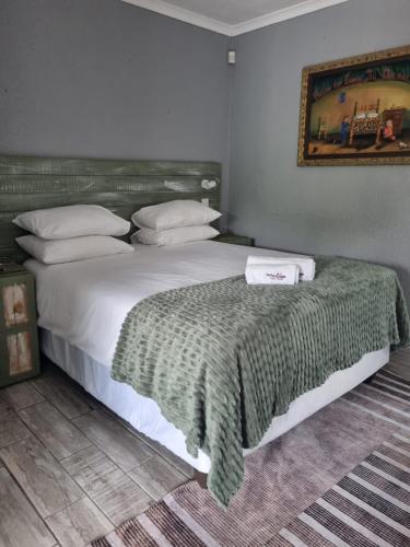 a bedroom with a bed with a green blanket on it at Northern Vine Guesthouse B&B Self-catering in Brackenfell