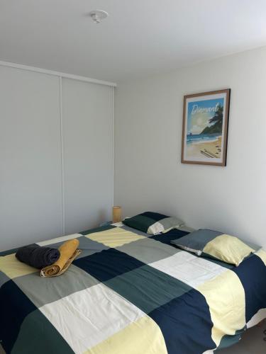 a bedroom with a bed with a striped blanket at Palme bleue t3 au diamant in Le Diamant