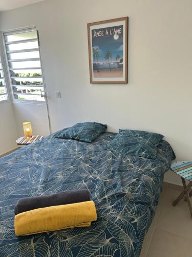 a bedroom with a bed with a yellow towel on it at Palme bleue t3 au diamant in Le Diamant