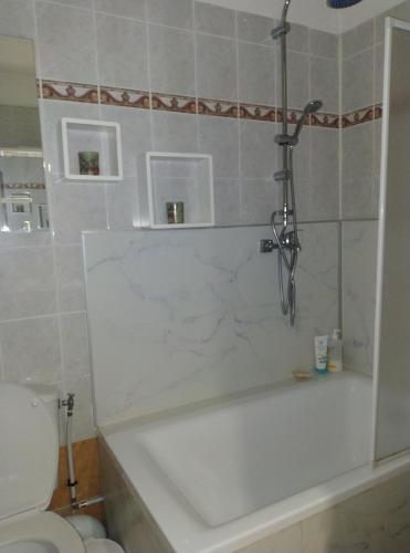 une salle de bain avec une baignoire blanche et des toilettes dans l'établissement Appartement 2p terrasse beau parc Gambetta-Fleurs, à Nice