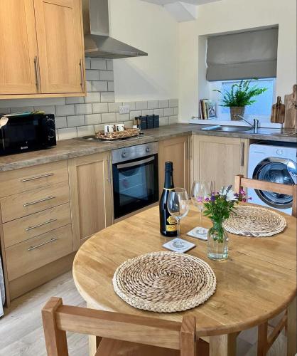 a kitchen with a wooden table with a bottle of wine at Farmhouse Apartment in Pembrokeshire