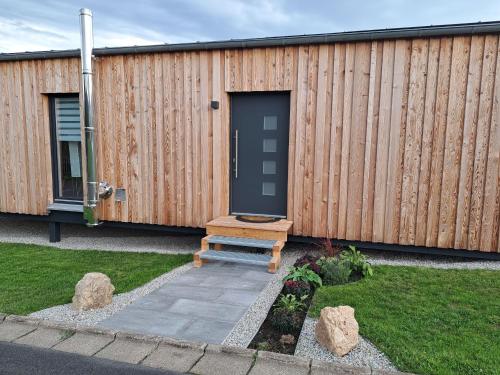 a wooden building with a black door and a bench at Ferienhaus - Fimo Haus in Nagel
