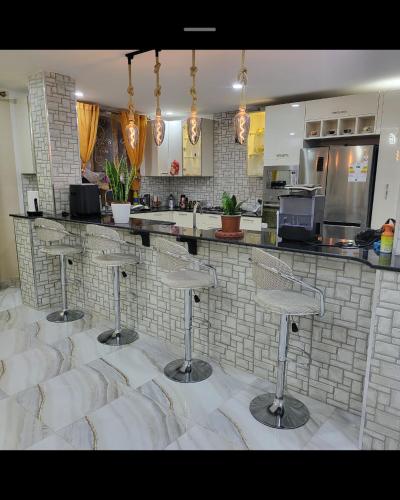 a kitchen with four bar stools in front of a counter at Large two story house in Le Hamiz