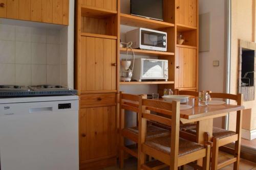une cuisine avec des armoires en bois et une table et des chaises dans l'établissement Appartement 2 pièces - 4 personnes - Saint Cyprien Plage SC150-220, à Saint Cyprien Plage