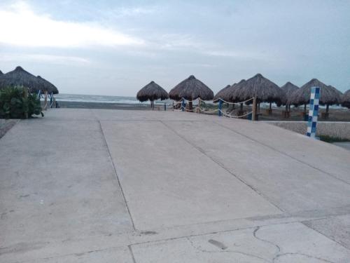 a beach with some straw umbrellas and the ocean at Hotel Arena Beach Cartagena in Cartagena de Indias