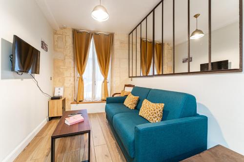 un salon avec un canapé bleu et une table dans l'établissement Appartements de charme au cœur de Bordeaux avec climatisation et rooftop, à Bordeaux