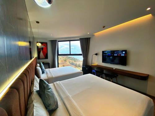 a hotel room with two beds and a flat screen tv at Apec Mandala Romantic Mui Ne in Ấp Thiẹn Ái