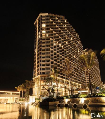 a tall building at night with palm trees in front of it at Apec Mandala Romantic Mui Ne in Ấp Thiẹn Ái