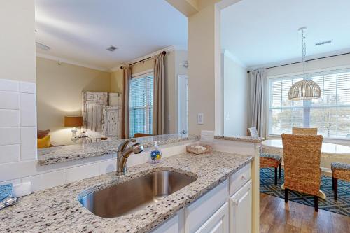 a kitchen with a sink and a living room at Creekwood --- 1400 Pebble Dr #1410 in The Plantations