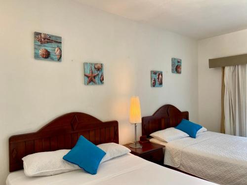 two beds in a bedroom with blue pillows at Agualina Kite Hotel Oceanfront Apartments in Cabarete