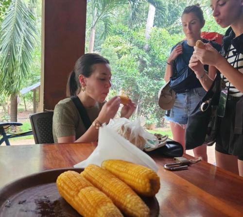 a group of women standing around a table eating corn at White House Inn in Lukasgoda