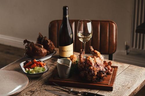 a table with a bottle of wine and chicken and vegetables at The Goudhurst Inn in Goudhurst