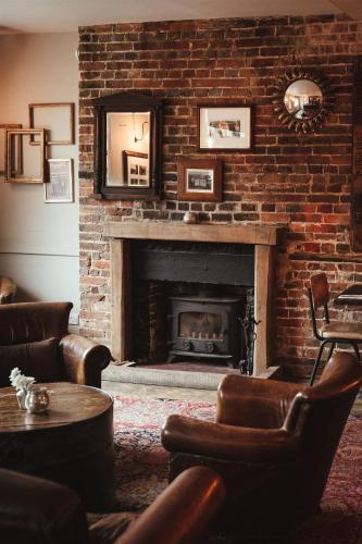 a living room with a brick fireplace with a mirror at The Goudhurst Inn in Goudhurst