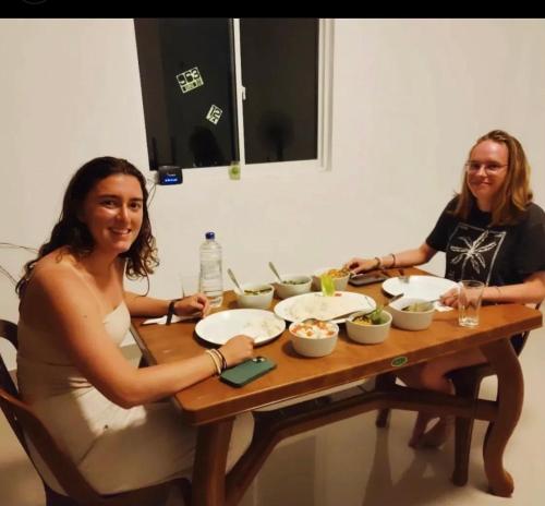 two women sitting at a table with bowls of food at White House Inn in Lukasgoda