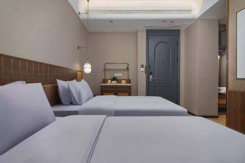 a bedroom with two beds and a blue door at Renjoy Hotel -Xiamen Zhongshan Road Pedestrian Street in Xiamen