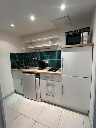 une petite cuisine avec des appareils blancs et du carrelage vert dans l'établissement Studio au cœur de Cannes, à Cannes