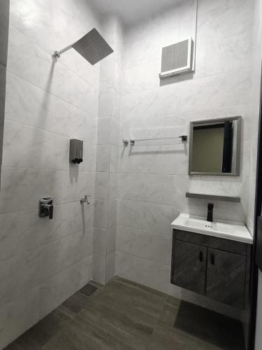 a bathroom with a shower with a sink and a mirror at RINA HOMESTAY Kemaman in Cukai