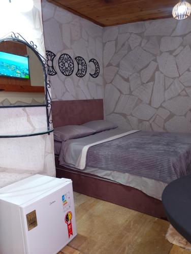a small room with a bed and a refrigerator at Recanto das Pedras hospedagem - Suíte 3 in São Thomé das Letras