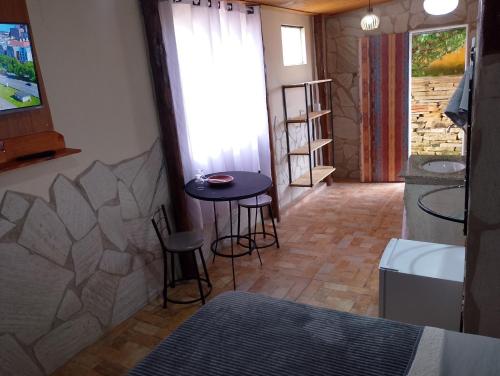 a room with a table and two stools in a room at Recanto das Pedras - Suíte 3 in São Thomé das Letras