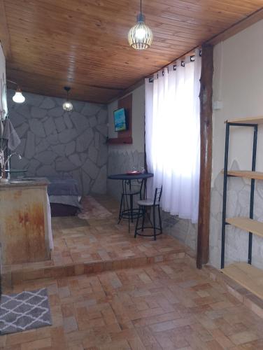 a living room with a table and a stone wall at Recanto das Pedras hospedagem - Suíte 3 in São Thomé das Letras