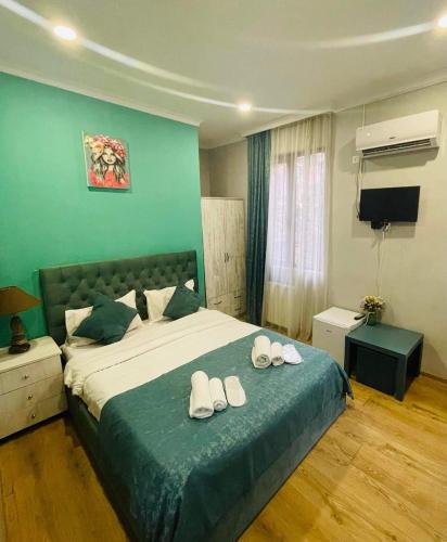 a bedroom with a large bed with slippers on it at Hotel Art Green in Tbilisi City