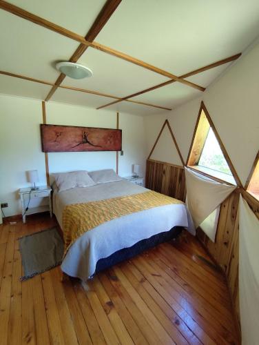 a bedroom with a bed in a room with wooden floors at Tierra de Domos in Villarrica