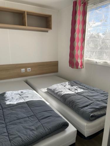 une chambre avec deux lits et une fenêtre dans l'établissement Quiet mobile home - Cc217 Les Charmettes 4 stars, aux Mathes