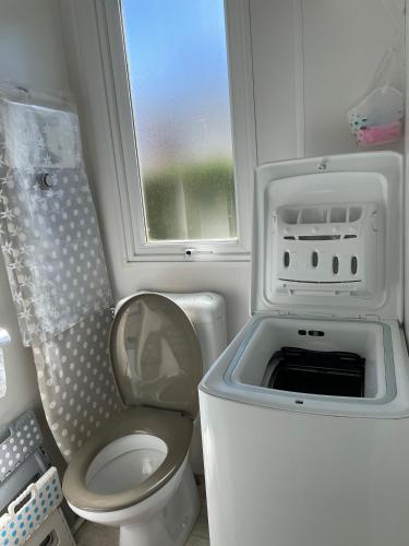Elle comprend une petite salle de bains pourvue de toilettes et d'une fenêtre. dans l'établissement Quiet mobile home - Cc217 Les Charmettes 4 stars, aux Mathes