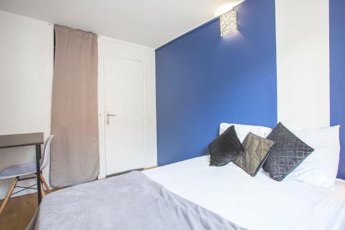 a bedroom with a blue wall and a bed with pillows at Colocation de luxe à Tourcoing avec jardin in Tourcoing