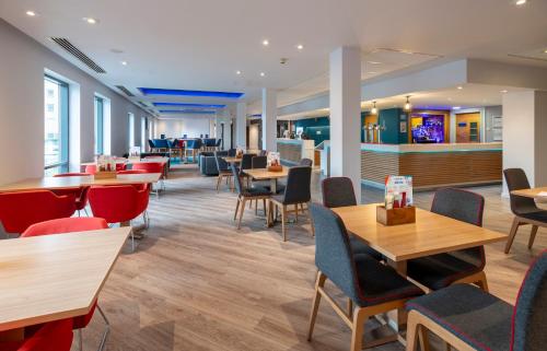a dining room with tables and chairs and a bar at Holiday Inn Express Stevenage by IHG in Stevenage