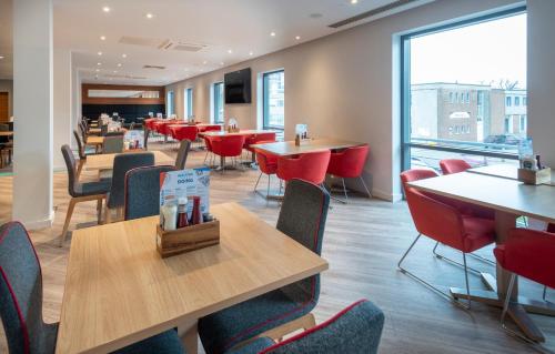 a dining room with tables and chairs and a cafeteria at Holiday Inn Express Stevenage by IHG in Stevenage