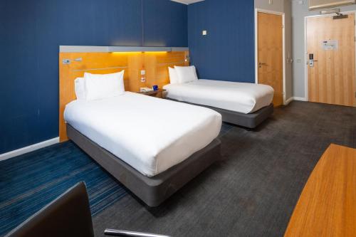 a hotel room with two beds and a desk at Holiday Inn Express Stevenage by IHG in Stevenage