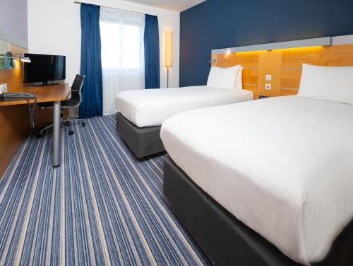 a hotel room with two beds and a desk at Holiday Inn Express Stevenage by IHG in Stevenage