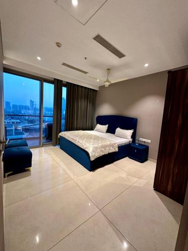 a bedroom with a blue bed and a large window at Luxe 2 BHK with Stunning Views in Gurgaon