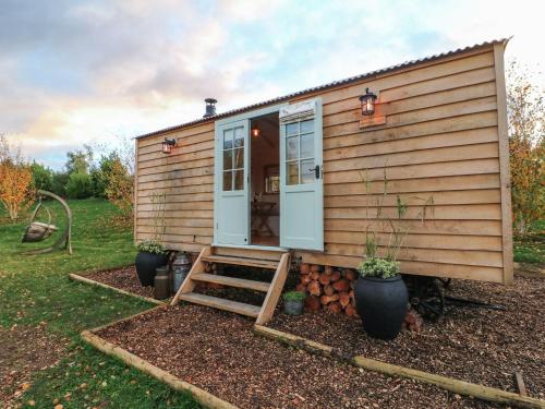 a tiny house with a porch and a door at Herbie's Shepherds Hut at Shepherds Lodge Retreat and Wellness in Nottingham