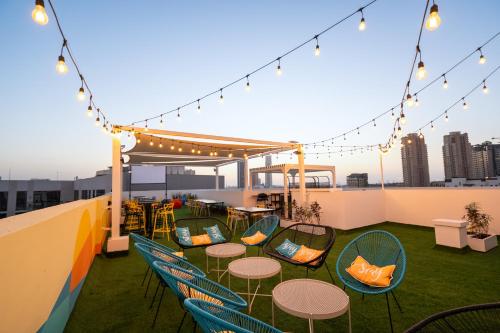 a rooftop patio with tables and chairs and lights at Izzzi Life Mint in Dubai