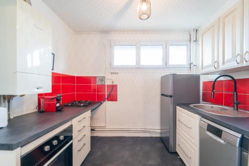 une cuisine avec des placards blancs et du carrelage rouge dans l'établissement Le Mignon - 20 min de Paris et Orly, à Vitry-sur-Seine
