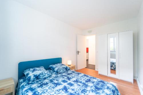 une chambre avec un lit bleu et une fenêtre dans l'établissement Le Mignon - 20 min de Paris et Orly, à Vitry-sur-Seine