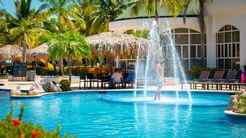 a fountain in a pool in front of a resort at La Ensenada Beach Resort in Tela