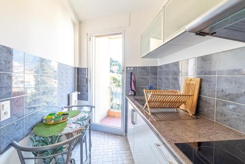 une cuisine avec un évier et une table avec des chaises dans l'établissement SAN FELICE - Charmant 2 pièces avec balcon et parking, à Menton