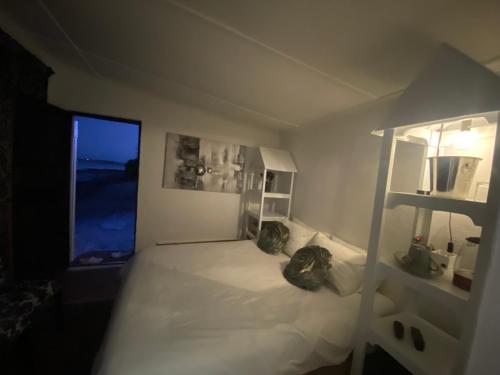 a bedroom with a white bed with a window at The Beach Shack Glamping & The Boat Shed in St Helena Bay