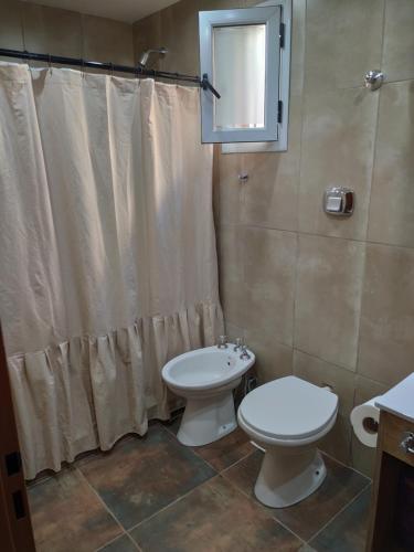a bathroom with a toilet and a shower curtain at Acogedor departamento tropical in Piñero