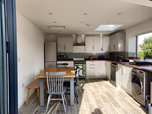 a kitchen with white cabinets and a table and chairs at 3 bed countryside cottage with use of private pool in Norwich