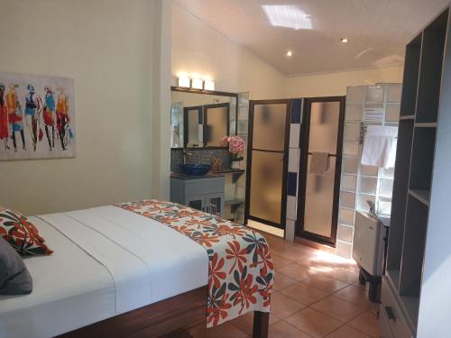 a bedroom with a bed and a kitchen with a refrigerator at Coyaba Tropical Elegant Adult Guesthouse in Manuel Antonio