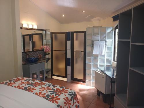 a bedroom with a bed and a bathroom with a mirror at Coyaba Tropical Elegant Adult Guesthouse in Manuel Antonio