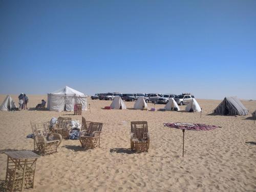 a group of tents and chairs on a sandy beach at Karam Siwa Camp in Siwa