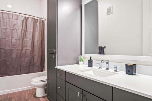 a bathroom with a sink and a toilet and a mirror at Luxurious New Unit 1Bd1Ba Pool, Golf Sim in Austin