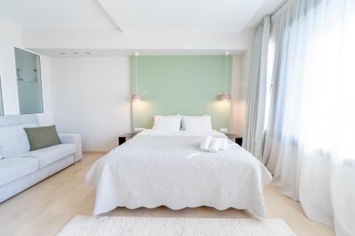 a white bedroom with a bed and a couch at Sea & the City in Thessaloniki
