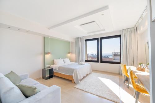 a white bedroom with a bed and a couch at Sea & the City in Thessaloniki