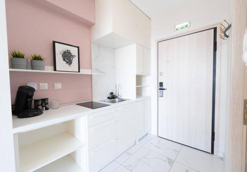 a white kitchen with a sink and a door at Sea & the City in Thessaloniki